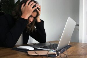 A woman sits at her desk, frustrated with a bad user experience on her computer.